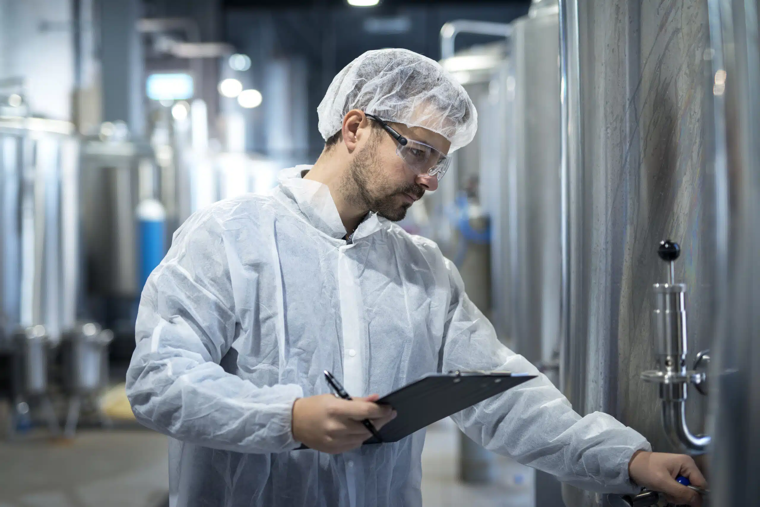 Techniker in Schutzkleidung kontrolliert eine Prozessanlage